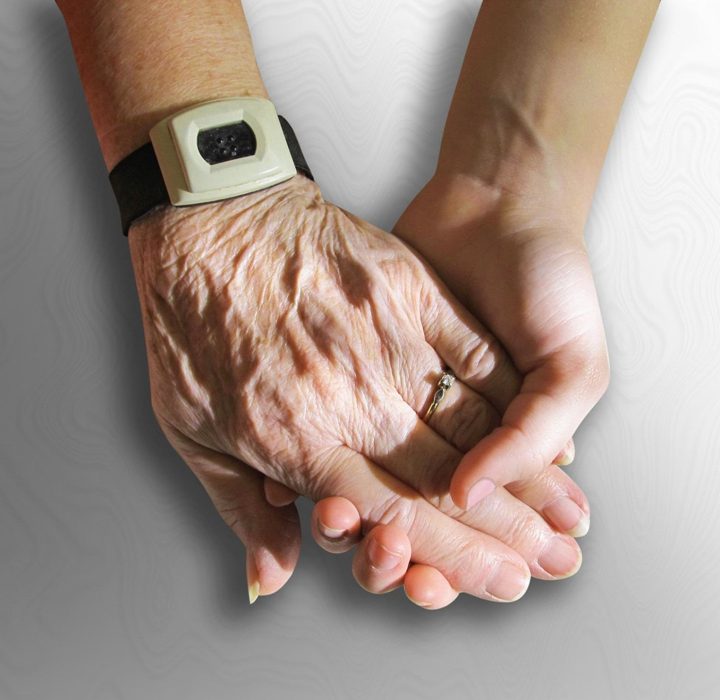 Pflegekraft hält die Hand einer pflegebedürftigen Person